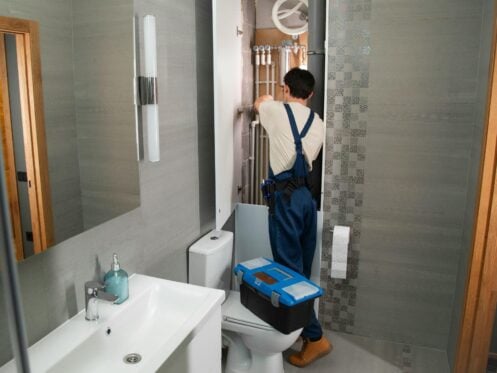 A plumber repairs a bathroom water system as part of plumbing services in Kansas City