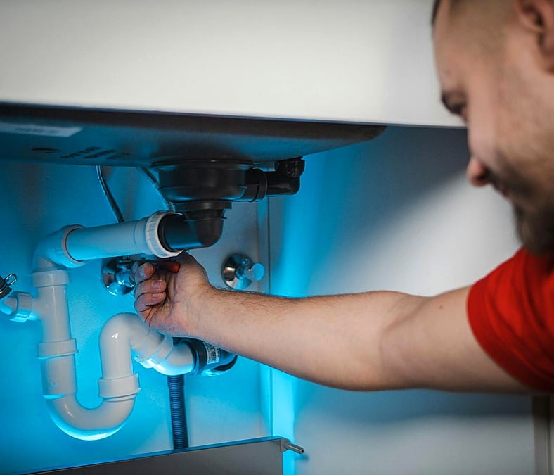 A plumber repairs sink pipes and fittings as part of plumbing services in Kansas City