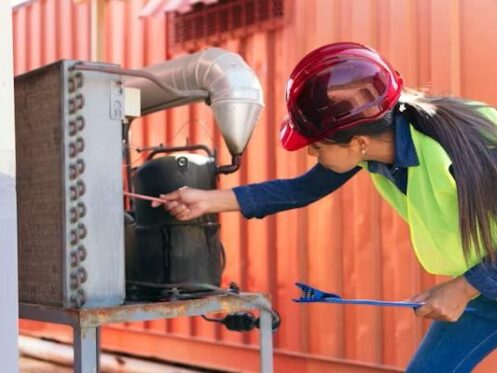 HVAC technician inspecting an air conditioning condenser during AC maintenance in Kansas City