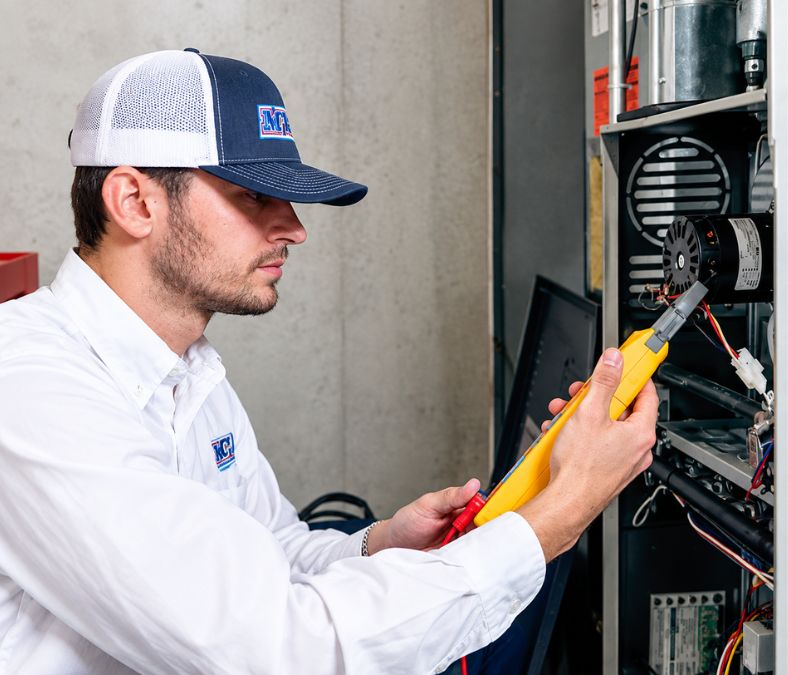 HVAC technician testing heat pump electrical components during installation