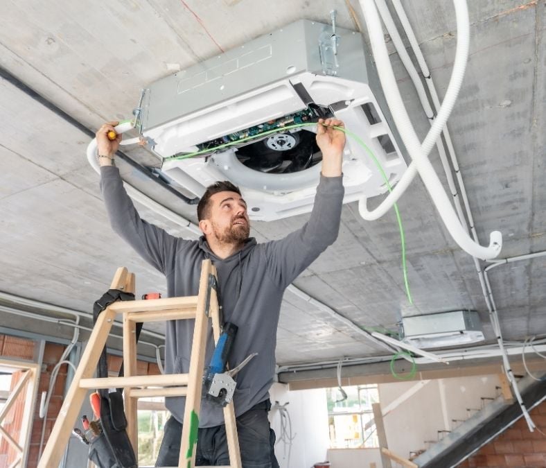Technician evaluating ductwork before HVAC installation in Kansas City